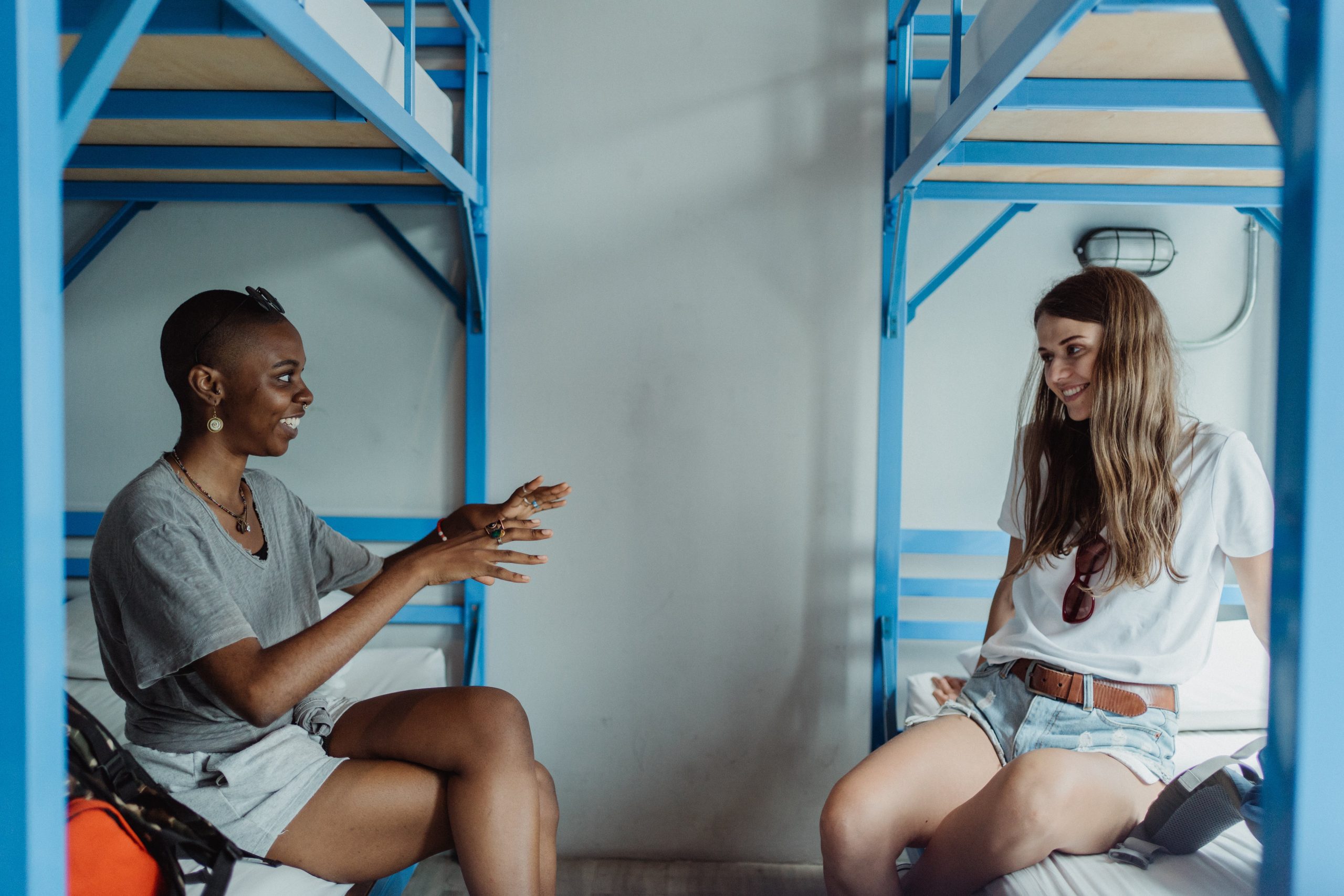 Women Sitting on Bunk Beds, Talking and Smiling